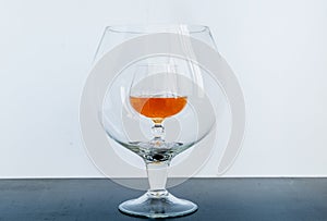 Small glass with whiskey inside big glass on black table