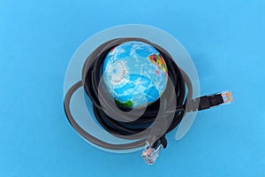 A small globe lies on a blue background surrounded by wires.