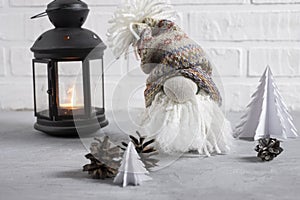 A small gnome in a cap with a bubo, beard and a big nose with a flashlight, Christmas tree candles and cones. Decor for christmas