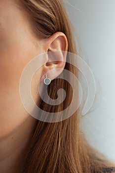 Small golden earring with green malachite on a young blonde woman