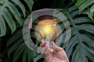 A small graduation cap put on a bright light bulb in a child's hand and a feeling of happiness on the graduation day.