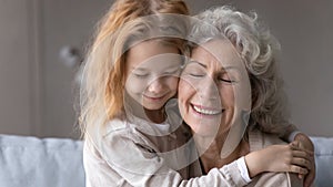 Small granddaughter hug old grandmother showing love