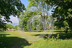 Small grassy football field between trees in czech town of Chabarovice with Ore mountains on background in spring