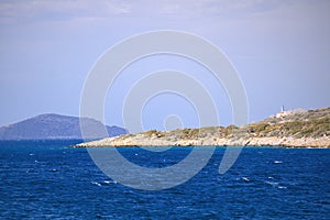 Small greek island on Mediterranean Sea, deep blue water, rocky islet with scant vegetation and some building. Islands near Crete.