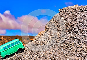 Small green bus toy on a rock  formation with a blurred background in the Canary Islands, Spain