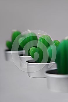 Small green candles in the shape of cacti stand diagonally on a gray background. Atmosphere of comfort. Decor in the room.