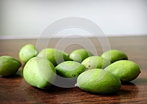 Small green mangoes on a wooden table