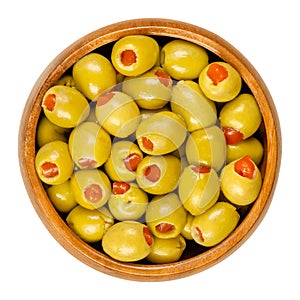 Pickled small green olives, filled with red sweet pepper in a wooden bowl