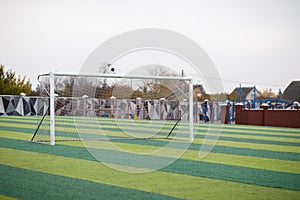 a small green soccer field and a white gate