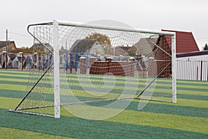 a small green soccer field and a white gate