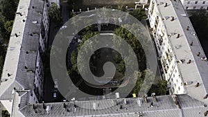 Small green summer courtyard surrounded by square shaped residential houses. Stock footage. Top aerial view of
