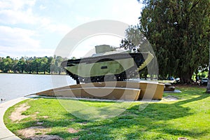 A small green tank sitting on the banks of the lake