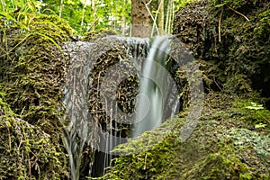 Small green waterfall in nature at the source of the emergence