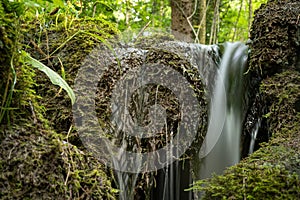 Small green waterfall in nature at the source of the emergence