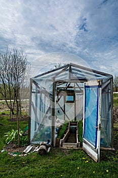 Small greenhouse with doors opened in a garden in spring at day