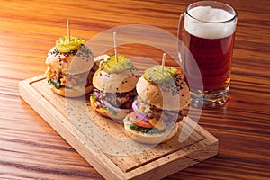 Small grilled burgers served to share with beer on rustic table