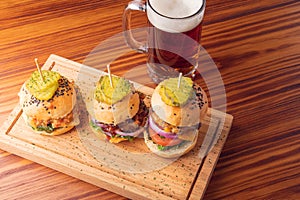 Small grilled burgers served to share with beer on rustic table