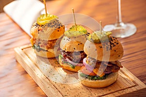 Small grilled burgers served to share on rustic table