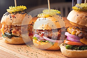 Small grilled burgers served to share on rustic table