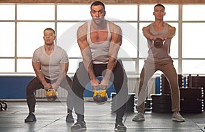 Small Group of Muscular Male Adults Working Out With Kettlebells