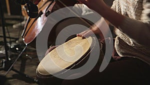small group of musicians play cello and percussion drums with hands