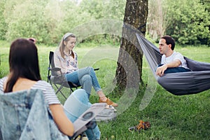 Small group of people enjoying conversation at picnic with social distance in summer park. Social distancing. Friends chilling in