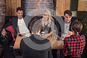 Small group of people talking, sitting sofa, coffee shop table i