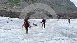 A small group of tourists with large backpacks are walking along the Miley glacier