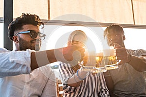 small group of young adult multiethnic friends toasting with three mugs of beer