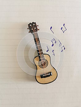 Small guitar with music notes drawing on notebook
