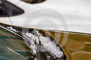 small hail ice balls on brown car hood after heavy summer storm