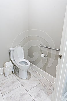 A small half bathroom with gray walls and a toilet with tile floors in a new construction house with a handicap railing