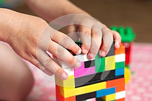 Small hands of the child collects the bright plastic colored Designer. Educational toys and Early learning