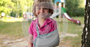 A small, handsome boy with a broken arm wrapped in a bandage.