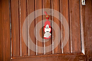 A small hanging red doll in the wooden brown door