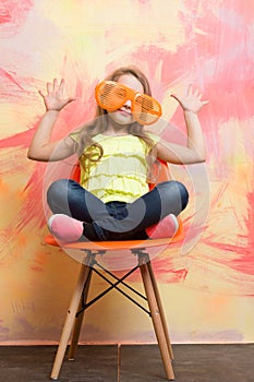 Small happy baby girl in orange sunglasses and yellow shirt