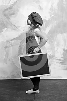 Small happy girl chef in hat, apron with blackboard