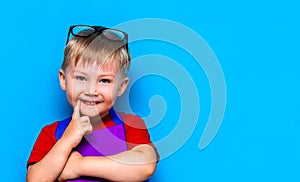 Small happy smiling boy with glasses on his head, book in hands, schoolbag on his shoulders. back to school. ready to school