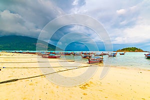 Small harbor with long tail boats at Ko Lipe island, Thailand, shortly before tropical storm. Big and heavy dark clouds above sea