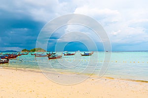 Small harbor with long tail boats at Ko Lipe island, Thailand, shortly before tropical storm. Big and heavy dark clouds above sea