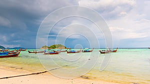 Small harbor with long tail boats at Ko Lipe island, Thailand, shortly before tropical storm. Big and heavy dark clouds above sea