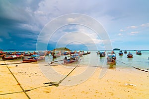 Small harbor with long tail boats at Ko Lipe island, Thailand, shortly before tropical storm. Big and heavy dark clouds above sea