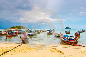 Small harbor with long tail boats at Ko Lipe island, Thailand, shortly before tropical storm. Big and heavy dark clouds above sea