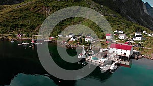 Small harbor town with pier at dark mountain foot aerial