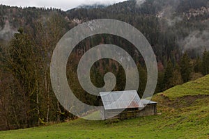 Small hay cabin in the Alpine Oberbayern region of Germany among hills covered with trees with colourful autumn foliage