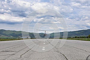 Small helicopter - tandem autogyro - taking off from a long wide tarmac runway