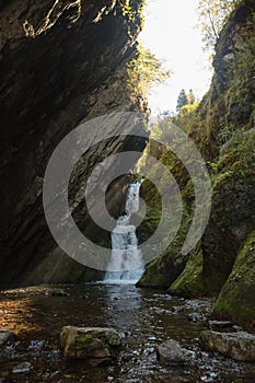 Small hidden waterfall in the forest in the cleft of the rock