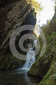 Small hidden waterfall in the forest in the cleft of the rock