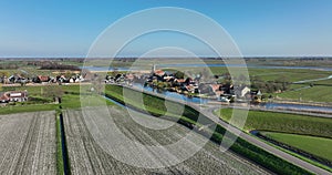 Small historic typical dutch polder farm village in green countryside sunny spring landscape with waterway and canals