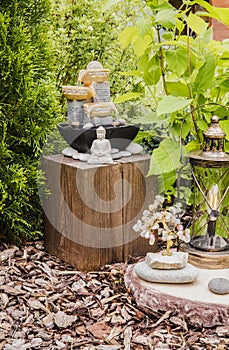 Small home garden private fountain with meditating Buddha statue between trees and bushes.